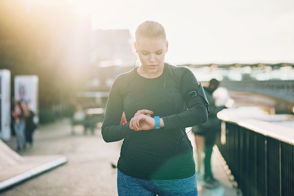 Woman checks fitness tracker while running | Setpoint theory